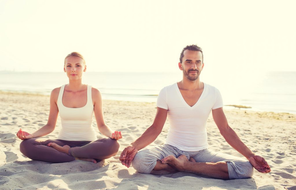 a couple sitting on the side enjoying a beachside yoga retreat Seminyak experience
