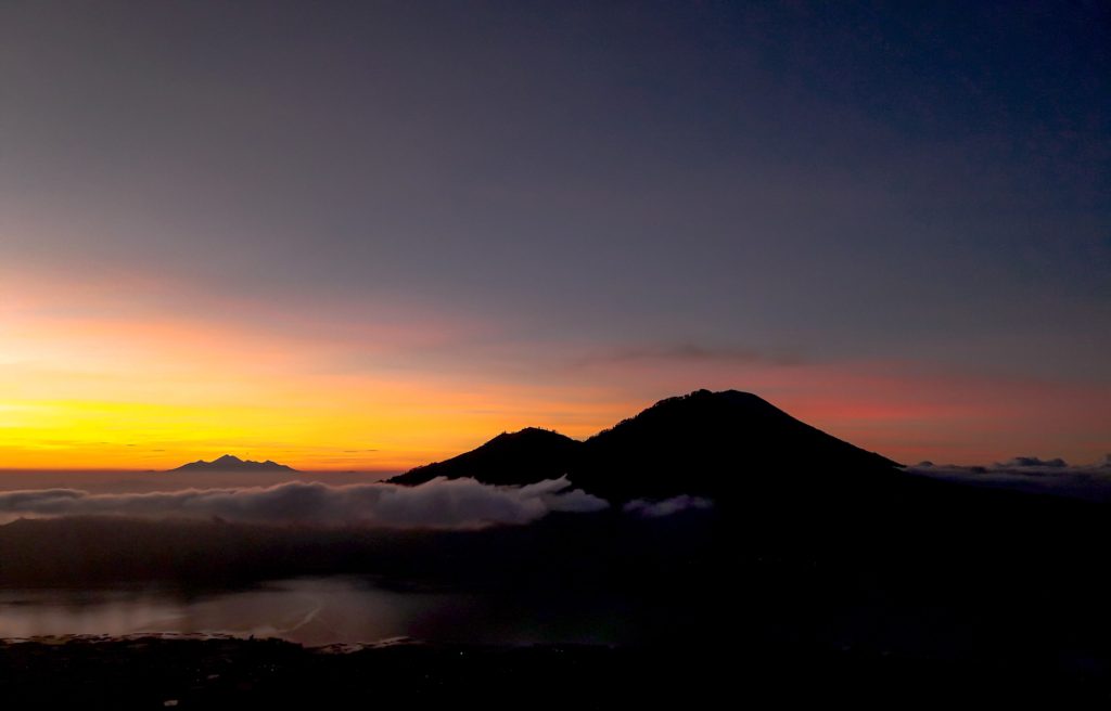doing hiking as part of outdoor activities in Bali, will be presented with an extraordinary sunrise view from the top of Mount Batur with gradations of pink, orange, purple, and blue colors