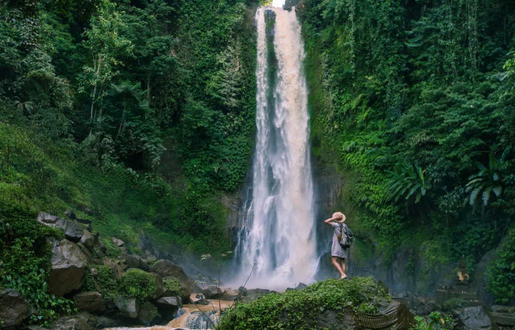 Gitgit waterfall with green trees around it adds a romantic impression to Bali honeymoon activities is the best place to visit in Bali for couples