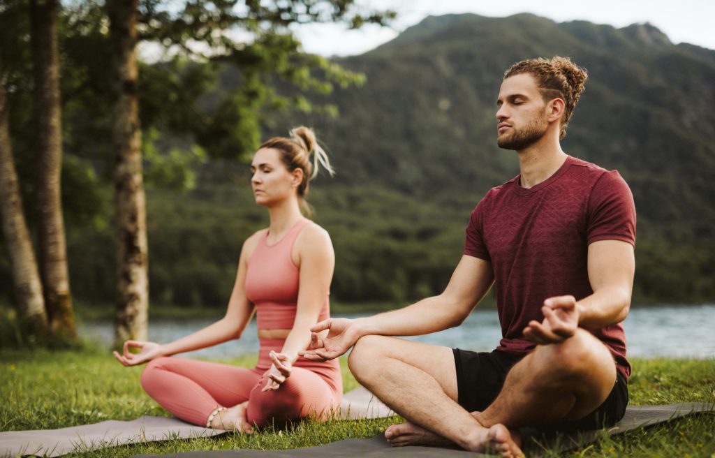 a man wearing a red sports shirt and his partner wearing a pink yoga set doing a yoga retreat Seminyak