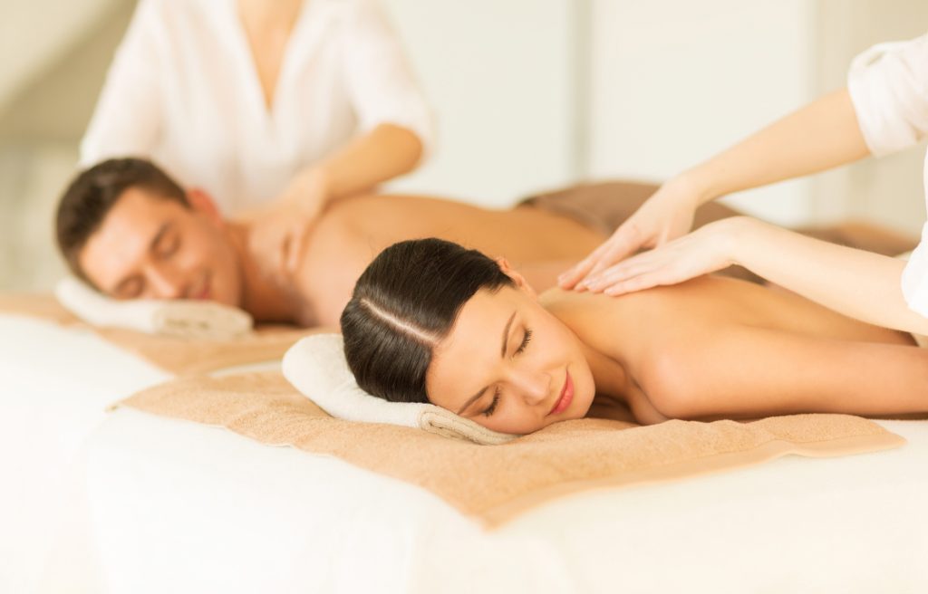newlyweds are lying side by side with their eyes closed enjoying a massage from a therapist at a spa in Bali Seminyak