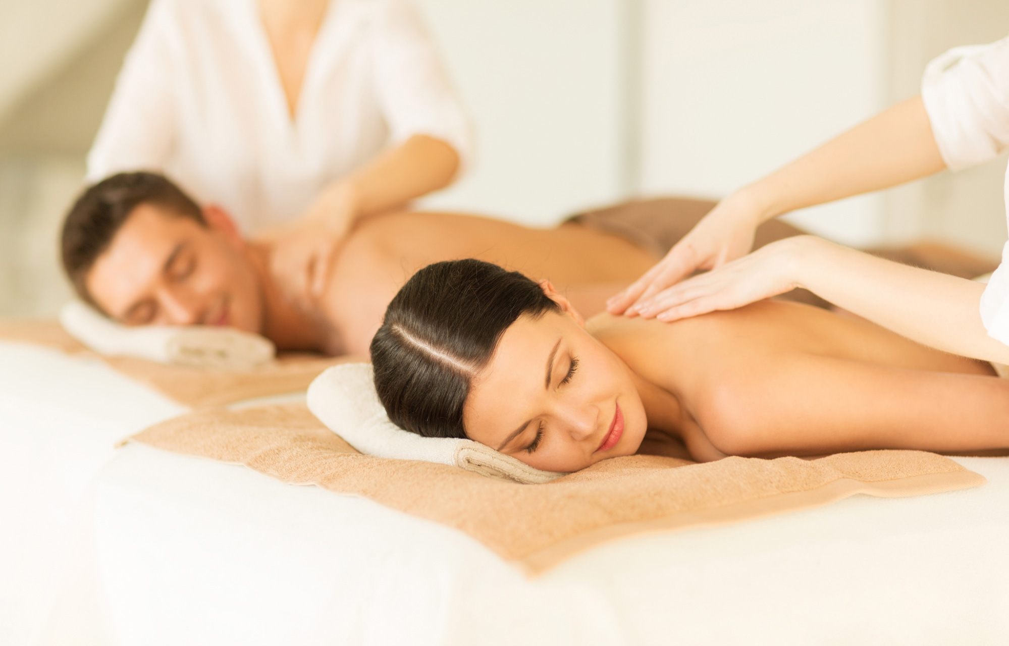 newlyweds are lying side by side with their eyes closed enjoying a massage from a therapist at a spa in Bali Seminyak